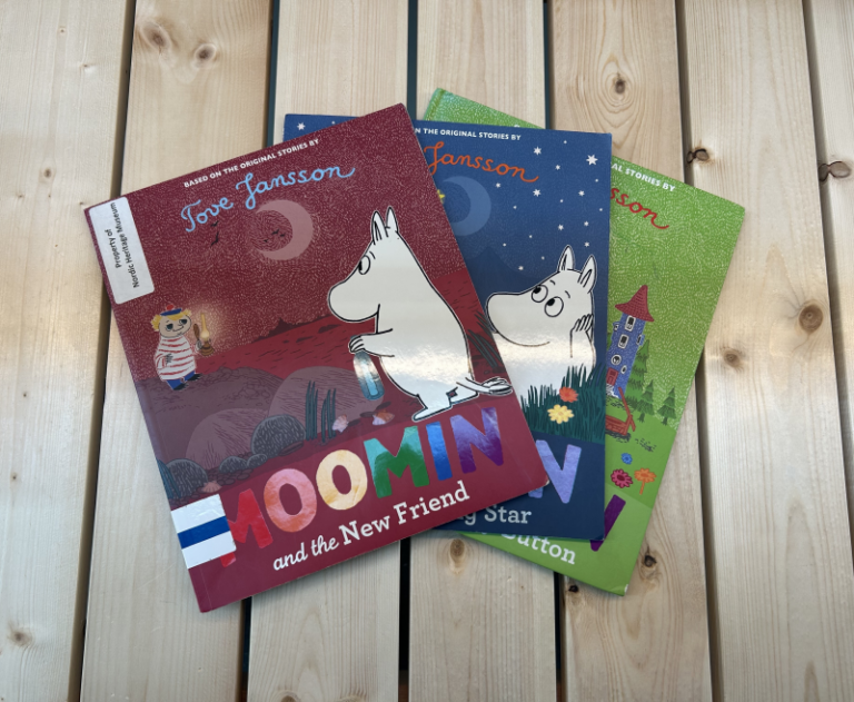 Three Moomin children's books on wooden table